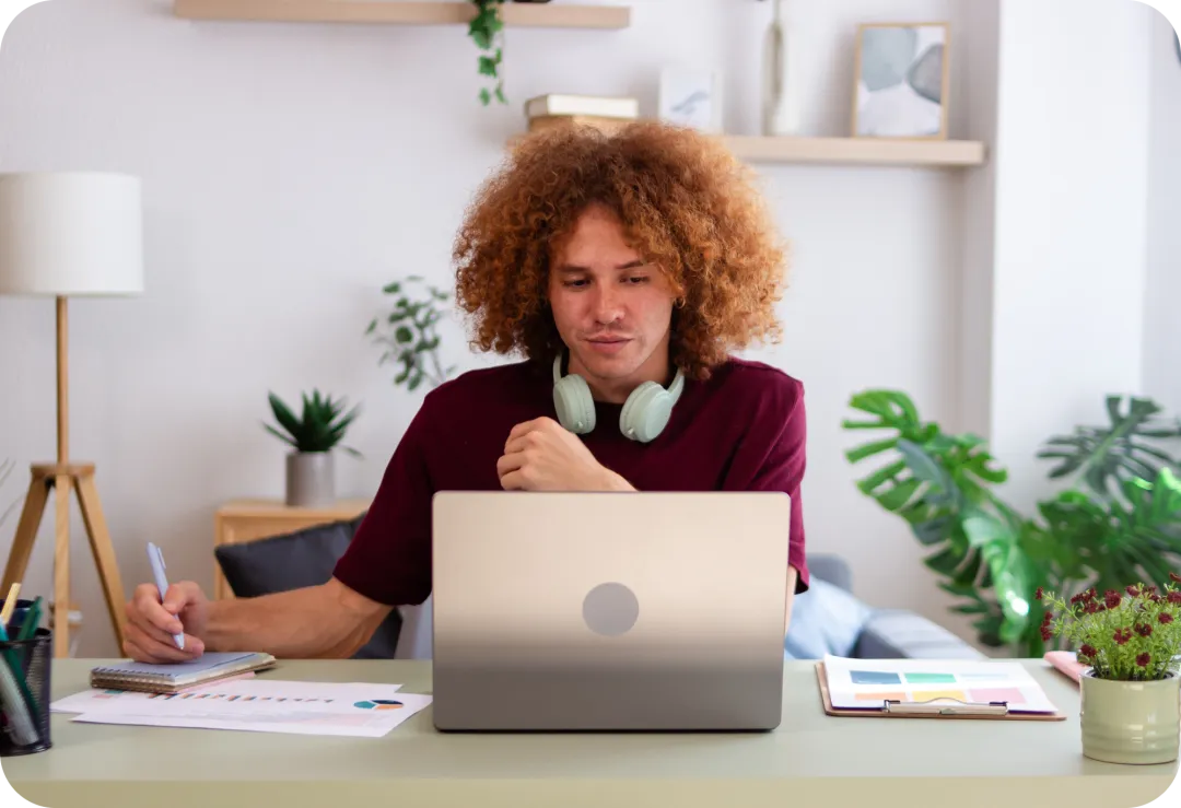 Man with curly hair sits at laptop