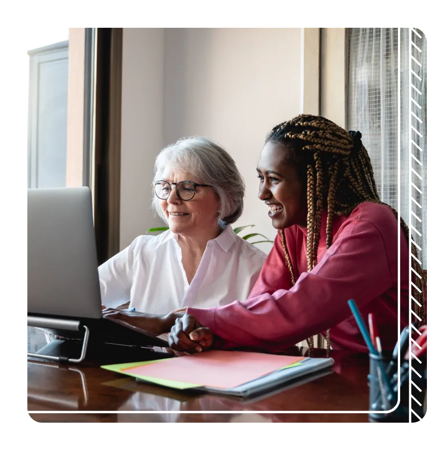 Two smiling women working together on a laptop