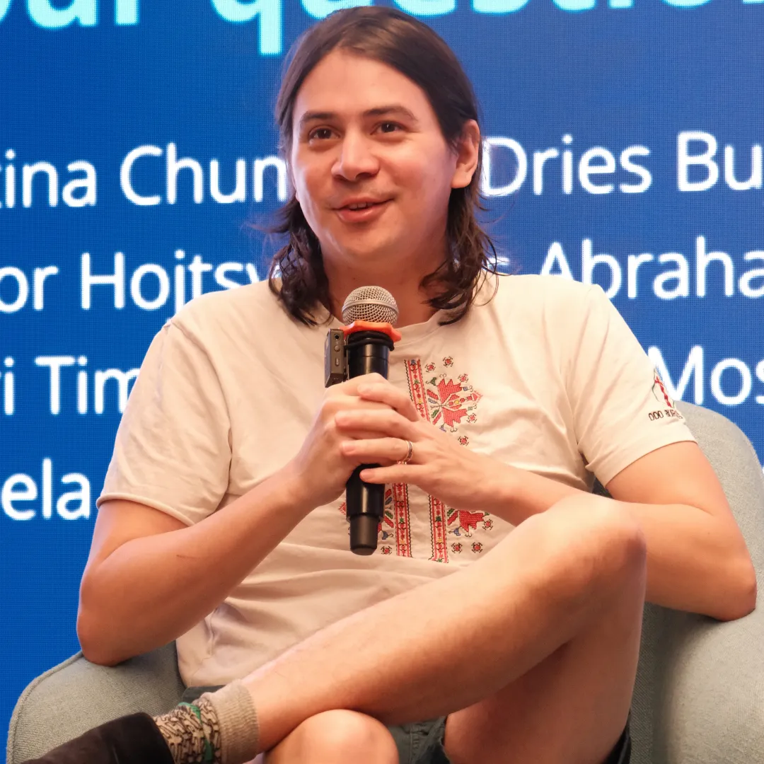 James Abrahams - Man with long brown hair, sitting in a chair with a microphone.