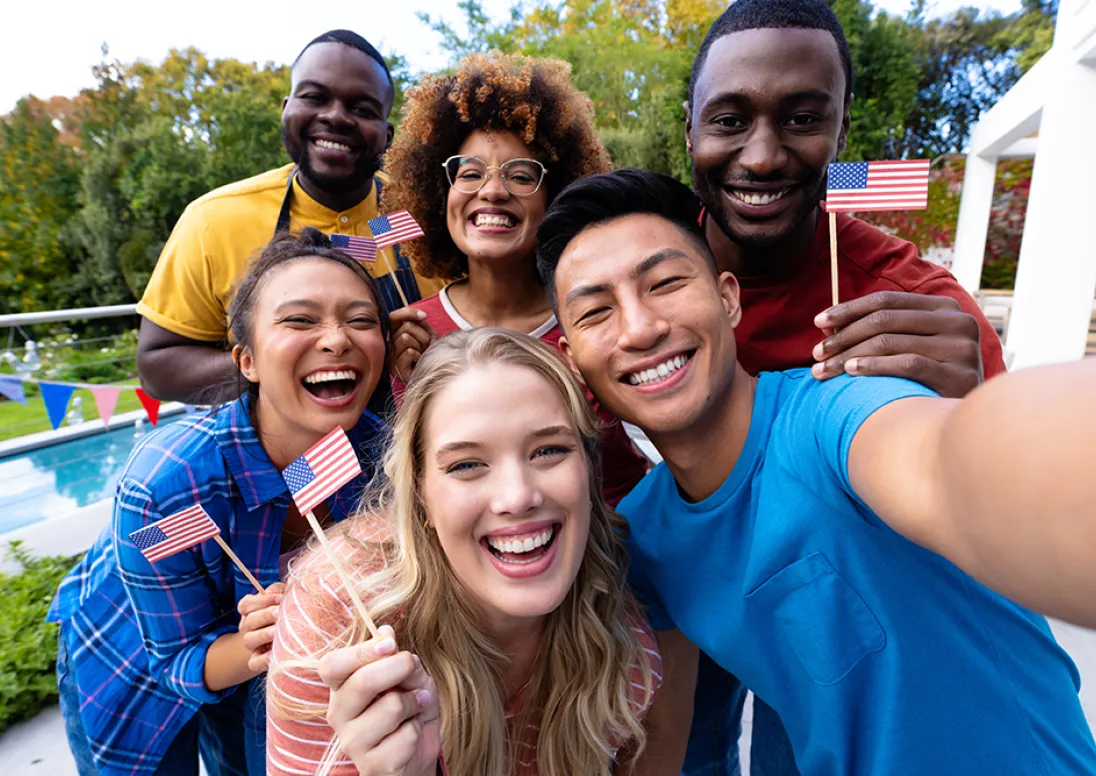 Diverse group of Americans posing for a selfie holding small flags