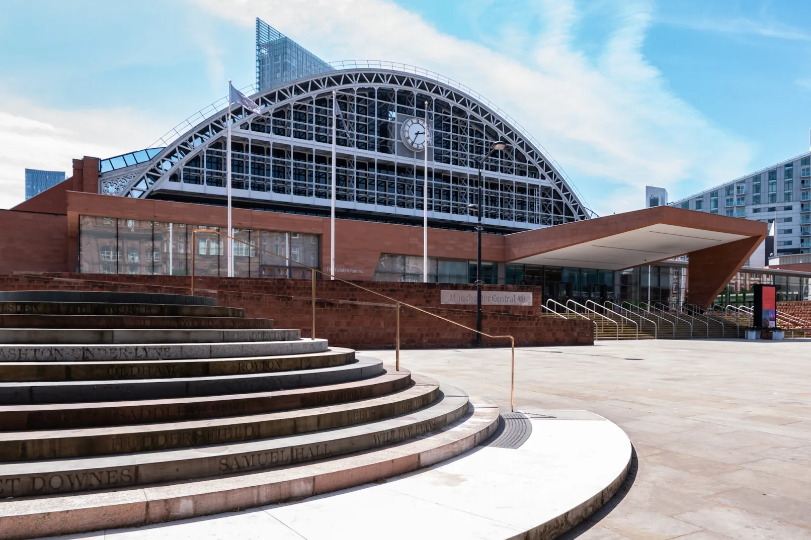 Manchester Central’s arched glass frontage and station clock, with curved steps and the venue entrance in the foreground
