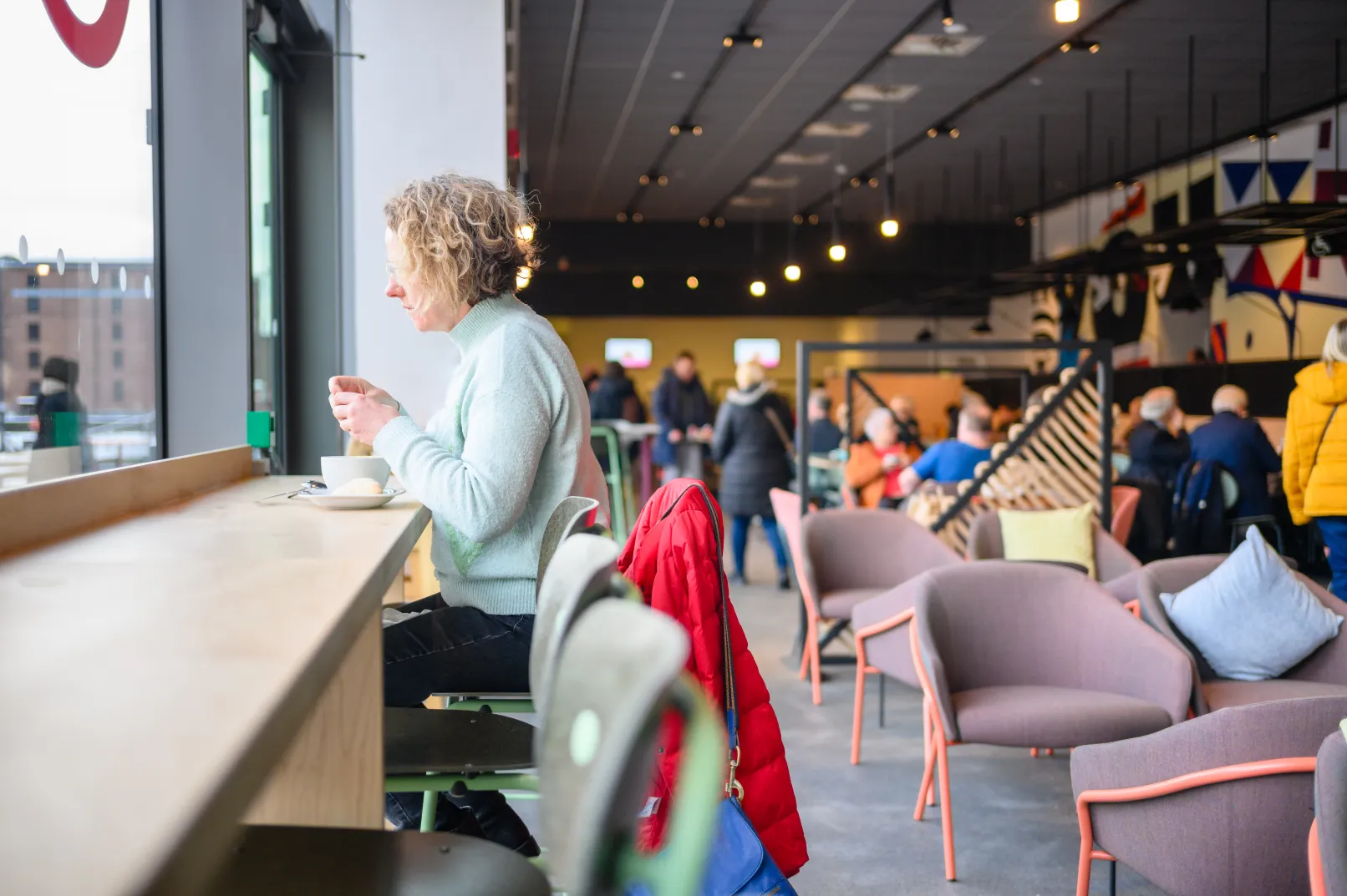 Visitors enjoying the Museum of Liverpool café, with seating beside large windows overlooking the waterfront