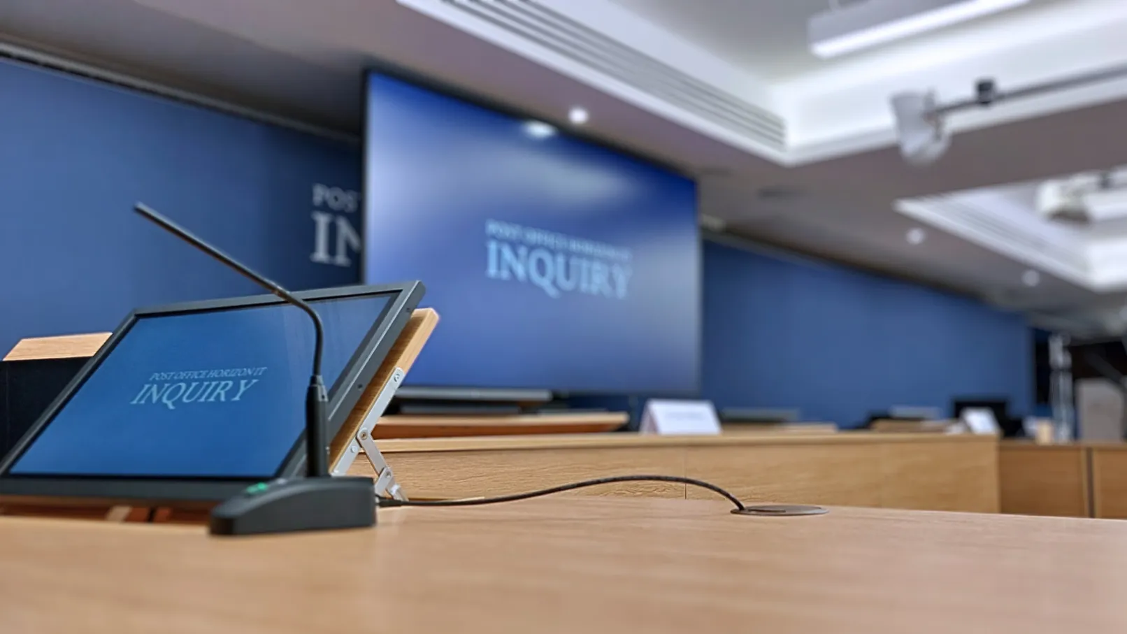 Empty hearing room with microphones, desks and Post Office Horizon IT Inquiry branding
