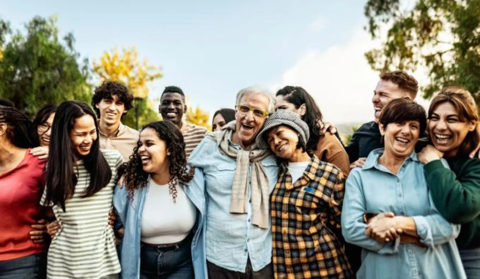 group of multigenerational adults gathered closely together outdoors, smiling
