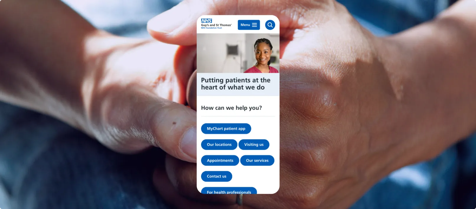 The GSTT homepage on mobile, in front of an image of hands