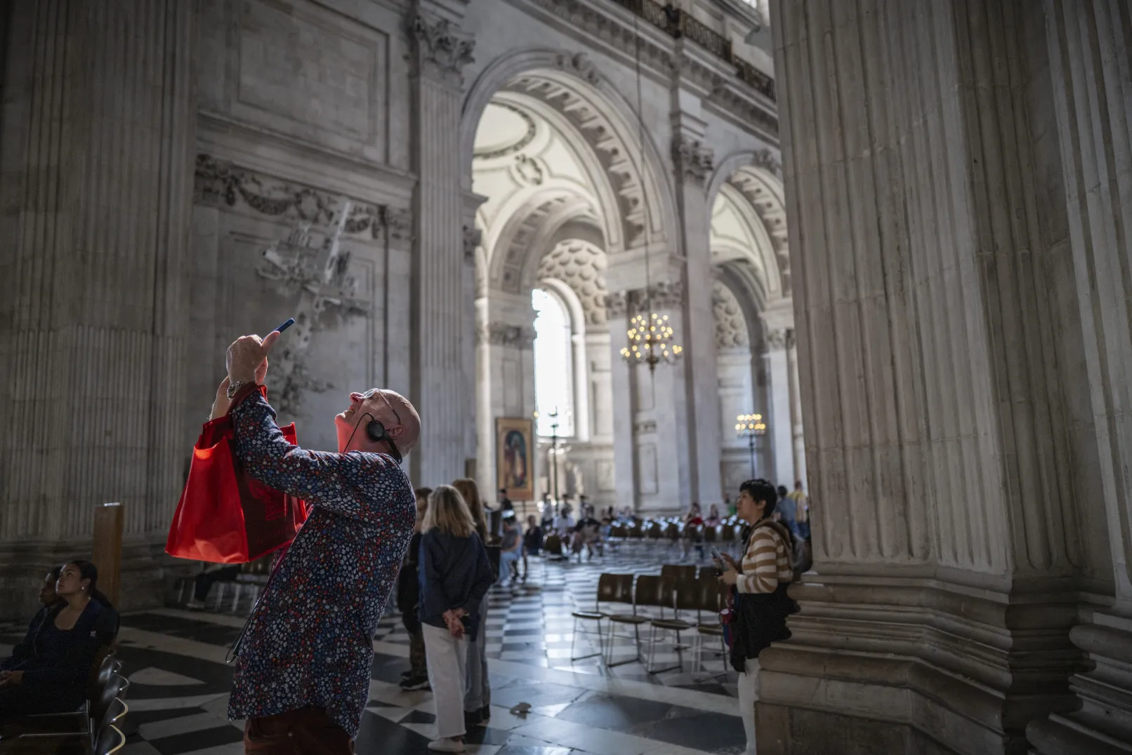 A visitor wearing an audio guide photographs the architecture inside St Paul’s Cathedral